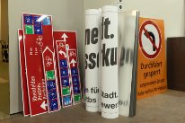 Diverse Wegweiser, Plakate und Schilder.