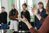 Musiklehrerin Imogen J. leitet Schülerinnen und Schüler mit ihren Händen beim Musizieren an. 