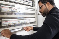 Gebäudetechniker Sivalackshan S. behebt eine elektronische Störung in einem Schaltschrank.