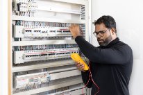Gebäudetechniker Sivalackshan S. prüft die Elektronik in einem Schaltschrank.