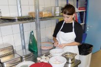 Küchenangestellte in Ausbildung in einer Küche beim Vorbereiten von Lebensmitteln. 